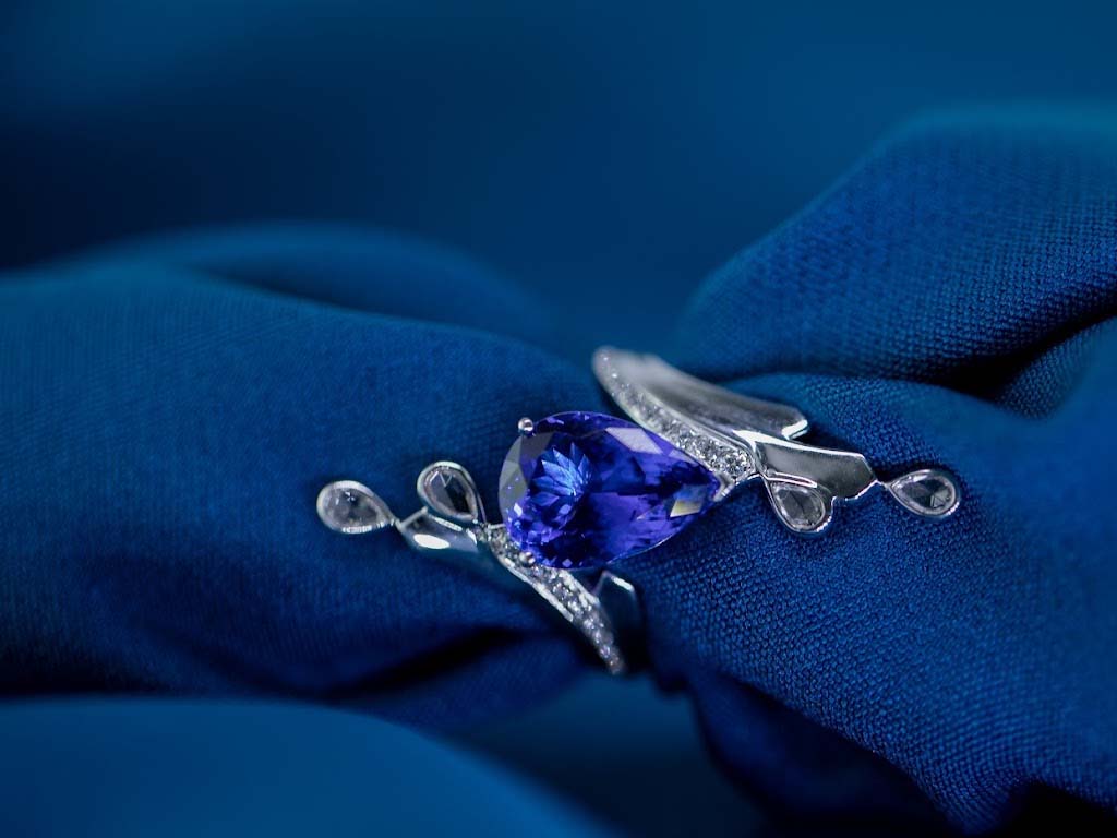 Close-up of a raw tanzanite gemstone juxtaposed with a polished tanzanite jewel, representing the transformation in the history of tanzanite processing